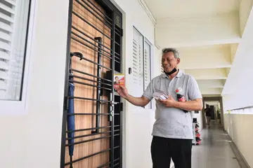EDAR RISALAH: Sukarelawan pasukan kempen calon Presiden, Encik Tan Kin Lian, melawat rumah ke rumah dan mengedarkan risalah di 181 Stirling Road.