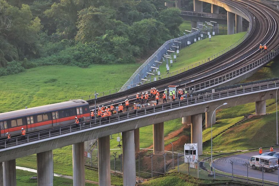 Kakitangan SMRT memeriksa gerabak kereta api yang terjejas di luar Depot Ulu Pandan kira-kira 1.45 petang pada 26 September. 