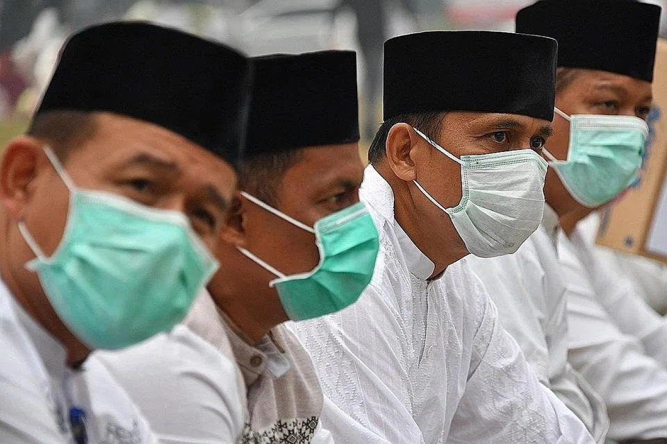 MINTA HUJAN: Penduduk Pekanbaru di wilayah Riau, yang kelihatan memakai pelitup, semalam mengadakan solat hajat bagi meminta hujan bagi meredakan kebakaran hujan yang menyebabkan jerebu rentas sempadan. - Foto AFP