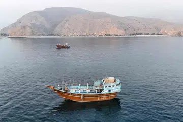 Bot dan kapal dilihat berlabuh berhampiran Semenanjung Musandam di utara Oman dekat Selat Hormuz pada 27 Jun 2026, ketika Iran dan Oman meneruskan perbincangan mengenai cadangan mengenakan bayaran perkhidmatan terhadap kapal yang melalui laluan perdagangan strategik itu.