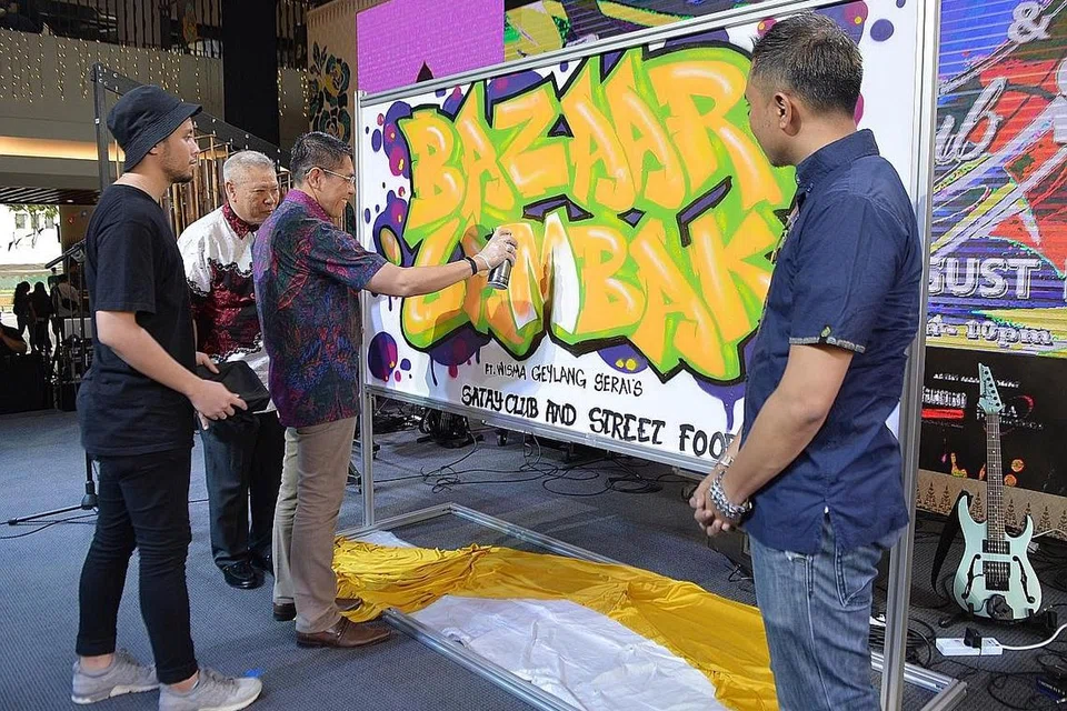 BAZAAR LAMBAK@WGS: Dr Maliki Osman (tiga dari kiri) memberi 'sentuhan terakhir' pada poster Bazar Lambak yang diadakan di Wisma Geylang Serai bermula hujung minggu lalu. Bazar tersebut yang mengetengahkan gerai-gerai makanan dan minuman serta acara menarik lain. Bazar tersebut diadakan selama 10 hari dari 16 hingga 25 Ogos 2019. - Foto BH oleh SHINTARO TAY