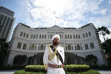 HOTEL BERSEJARAH: 'Doorman' di Hotel Raffles, Encik Narajan Singh, bergambar berlatarbelakangkan bangunan gah hotel bersejarah itu. Beliau juga adalah duta jenama yang telah bekerja di sana sejak 1992. - Foto BH oleh LIM YAOHUI