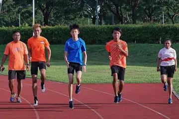 SASAR BERI YANG TERBAIK: Pasukan atletik para belia Singapura bagi Sukan Para Belia Asia 2021 terdiri daripada (dari dua dari kiri) Ariq, Maveric, Imran dan Nurhayati. Mereka diperhatikan oleh ketua jurulatih Hosni (paling kiri) ketika satu latihan di Trek Latihan Kallang baru-baru ini. - Foto BH oleh KHALID BABA