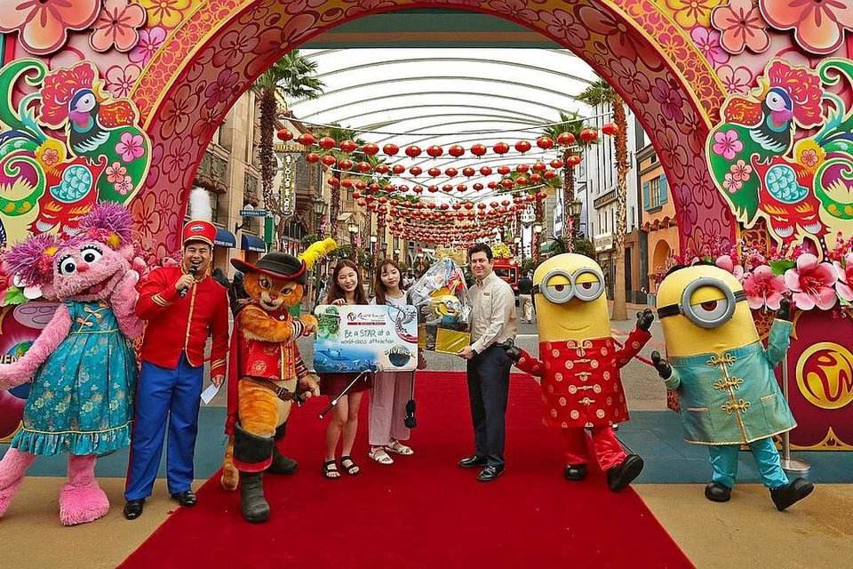 25 JUTA PELAWAT: Dua pelajar wanita dari Korea Selatan - Cik Eun Ji-Kim (empat dari kiri) and Cik Seon Mi-Hwang - menerima hamper daripada Naib Presiden Kanan Daya Tarikan Resorts World Sentosa, Encik Jason Horkin, kerana mereka merupakan pelawat yang ke-25 juta di Universal Studios Singapore. - Foto UNIVERSAL STUDIOS SINGAPORE