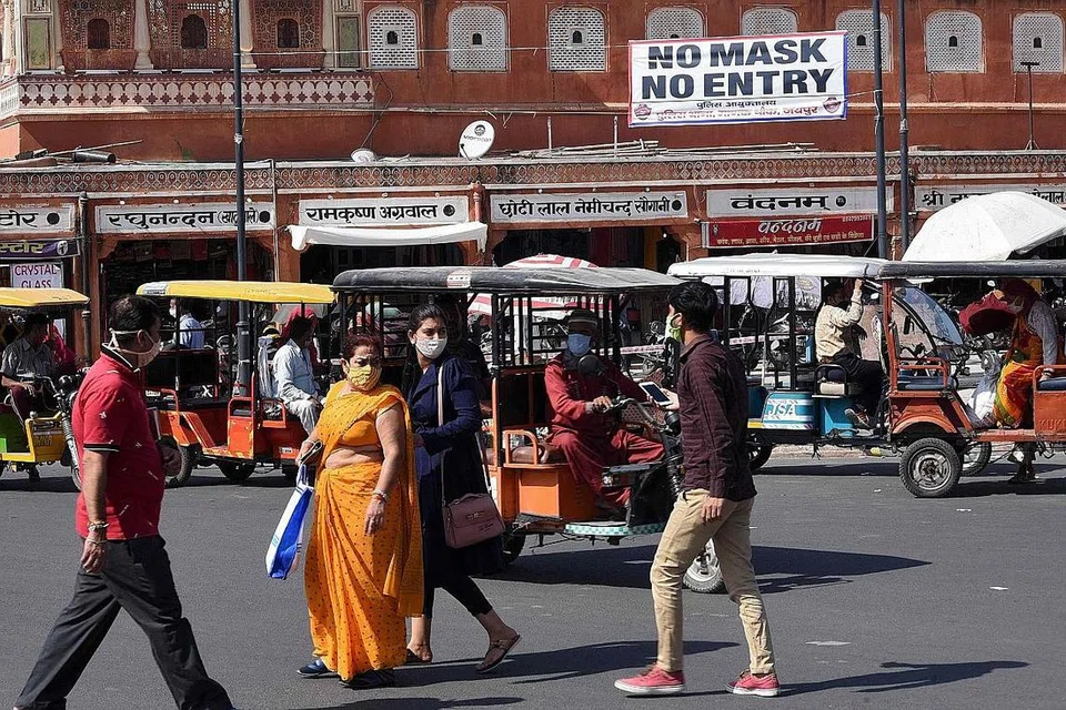 PAKAI PELITUP: Beberapa penduduk India dilihat memakai pelitup semasa mereka pergi ke sebuah pasar sedang kes jangkitan Covid-19 di negara itu melebihi 8.5 juta kes. - Foto AFP