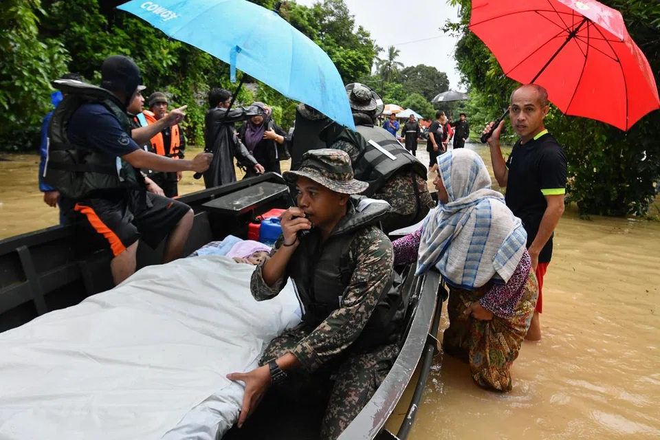 Anggota Angkatan Tentera Malaysia (ATM) membantu penduduk Kampung Kuala Nal, Kuala Krai, Kelantan, berpindah, termasuk warga emas, Cik Zainab Mat Dhari, 76 tahun, yang terlantar sakit.