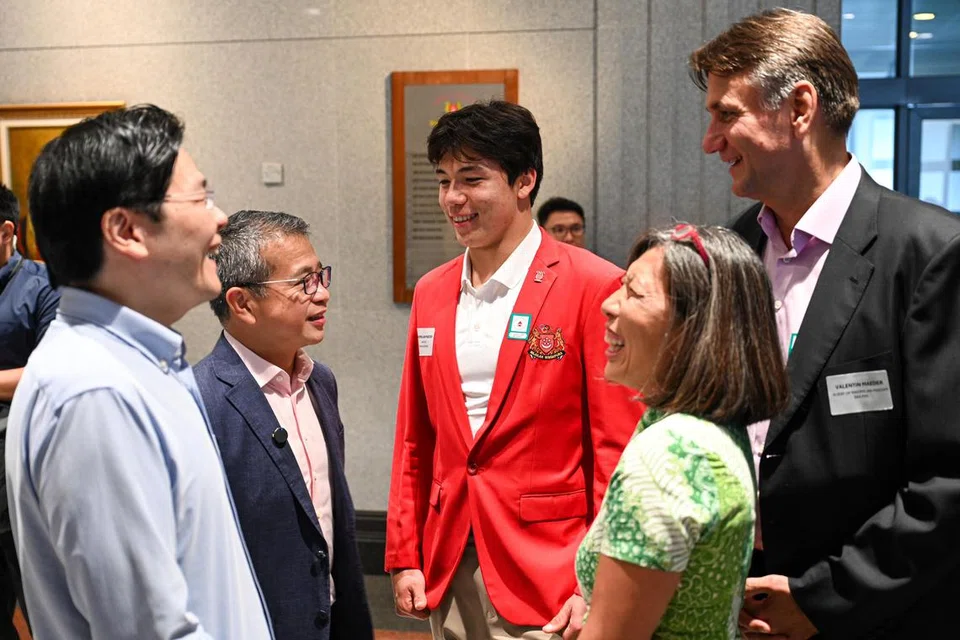 (Dari kiri) Perdana Menteri, Encik Lawrence Wong dan Menteri Kebudayaan, Masyarakat dan Belia, Encik Edwin Tong, berinteraksi dengan pemenang pingat gangsa dalam acara sukan luncur lelayang di Olimpik Paris 2024, Maximilian Maeder. Bersamanya adalah ibu bapa Maeder, Hwee Keng and Valentin Maeder.