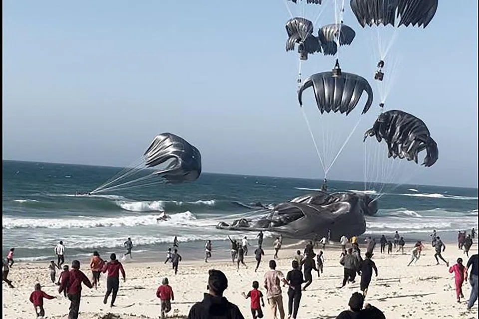 Penduduk Gaza berlari ke arah payung terjun yang membawa bungkusan makanan dan digugurkan dari pesawat Amerika Syarikat di pantai Jaluran Gaza pada 2 Mac. 