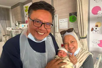 Selebriti Suhaimi Yusof (kiri) dan isterinya, Cik Siti Yuhana Sulaiman (kanan), bergambar bersama cucu pertamnya, Akiff Muaz Amirul, pada 21 Julai.
