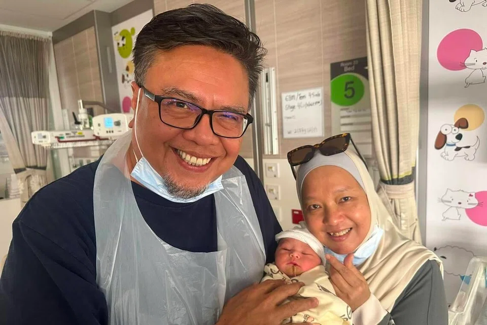 Selebriti Suhaimi Yusof (kiri) dan isterinya, Cik Siti Yuhana Sulaiman (kanan), bergambar bersama cucu pertamnya, Akiff Muaz Amirul, pada 21 Julai.