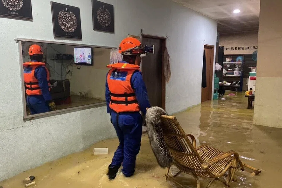 Anggota Angkatan Pertahanan Awam (APM) meninjau keadaan sebuah rumah di Bandar Baharu, Kedah, yang dinaiki banjir pada malam 23 Oktober.