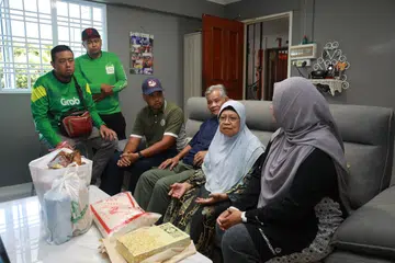 Dua sukarelawan Grab bersama Presiden Persatuan Muhammadiyah, Ustaz Muhammad Azri Azman (tiga dari kiri), dan Setiausaha Umum, Persatuan Muhammadiyah, Cik Roszanah Abdul Salim (kanan), bertemu penerima bantuan mereka, Cik Siti Asmaniah (dua dari kanan) dan suaminya. 