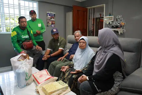 Dua sukarelawan Grab bersama Presiden Persatuan Muhammadiyah, Ustaz Muhammad Azri Azman (tiga dari kiri), dan Setiausaha Umum, Persatuan Muhammadiyah, Cik Roszanah Abdul Salim (kanan), bertemu penerima bantuan mereka, Cik Siti Asmaniah (dua dari kanan) dan suaminya. 