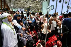 BERSAMA KELUARGA: Cik Muznah Moss (kiri) bersama suaminya, Encik Ramli Rahmat (berkerusi roda) dan saudara-mara mereka di Lapangan Terbang Changi semalam.