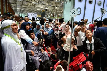 BERSAMA KELUARGA: Cik Muznah Moss (kiri) bersama suaminya, Encik Ramli Rahmat (berkerusi roda) dan saudara-mara mereka di Lapangan Terbang Changi semalam.