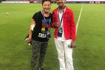 PENCETUS INSPIRASI: Syah Riszuan (kanan) senangi sikap keibuan guru muziknya, Aunty KP (Kuo Po). Foto ini dirakam di Stadium Negara tahun lalu ketika Syah menyanyikan Lagu Kebangsaan, 'Majulah Singapura' sempena perasmian pusingan kelayakan Piala Dunia Fifa. - Foto ihsan SYAH RISZUAN