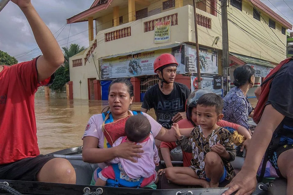 SELAMATKAN KELUARGA: Wanita bersama anak kecil ini dibantu mencari perlindungan di tempat lebih selamat. - Foto AFP