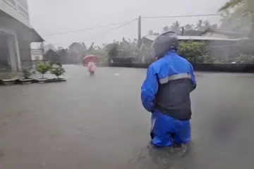 Seorang lelaki  berdiri dalam air banjir ketika hujan lebat akibat laluan taufan Mekkhala yang bergerak menuju Jepun, di Pingtung, Taiwan pada 25 Jun 2026. Gambar ini dirakam daripada video yang dibekalkan pihak ketiga.