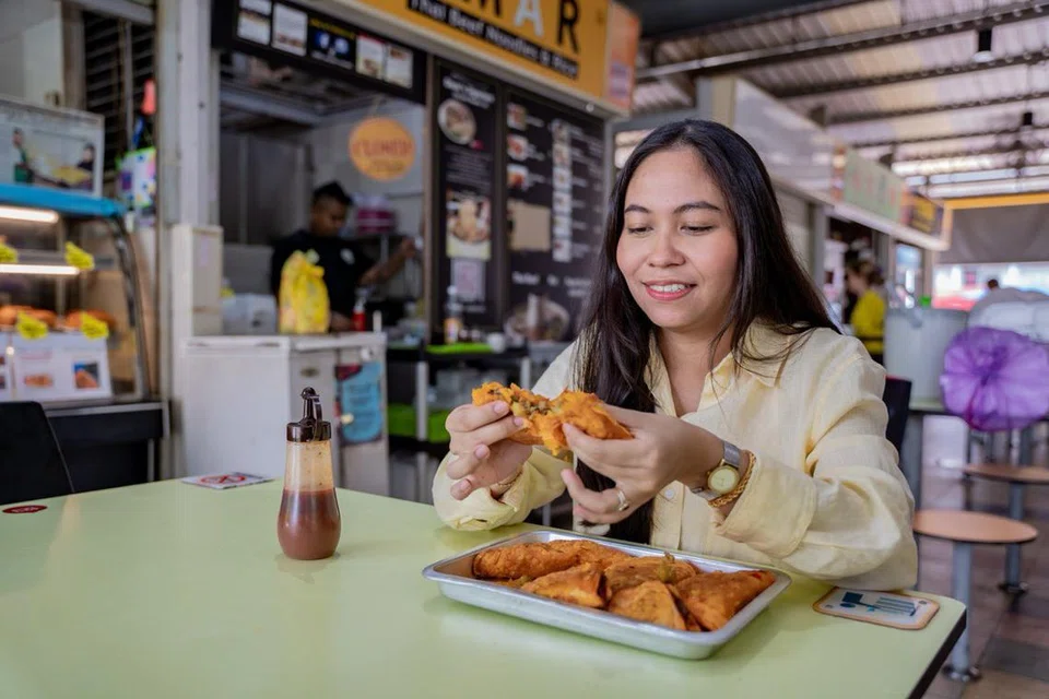 SELESA DI PUSAT PENJAJA: Penulis Nur Syuhrah Hassan di Pusat Penjaja Circuit Road, menikmati karipap bhai dari gerai Isha Curry Puff.