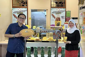 SALING MELENGKAPI: Pengarah Urusan Jumain Sataysfaction, Cik Samsiah Suliman (kanan) dan Ketua Pegawai Kewangan, Old Chang Kee, Encik Song Yeow Chung (kiri) bersatu tenaga untuk saling melengkapi produk masing-masing. Jumain Sataysfaction membekalkan sate ke cawangan Old Chang Kee. - Foto JUMAIN SATAYSFACTION