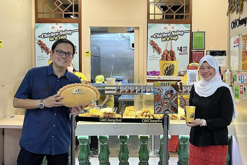 SALING MELENGKAPI: Pengarah Urusan Jumain Sataysfaction, Cik Samsiah Suliman (kanan) dan Ketua Pegawai Kewangan, Old Chang Kee, Encik Song Yeow Chung (kiri) bersatu tenaga untuk saling melengkapi produk masing-masing. Jumain Sataysfaction membekalkan sate ke cawangan Old Chang Kee. - Foto JUMAIN SATAYSFACTION