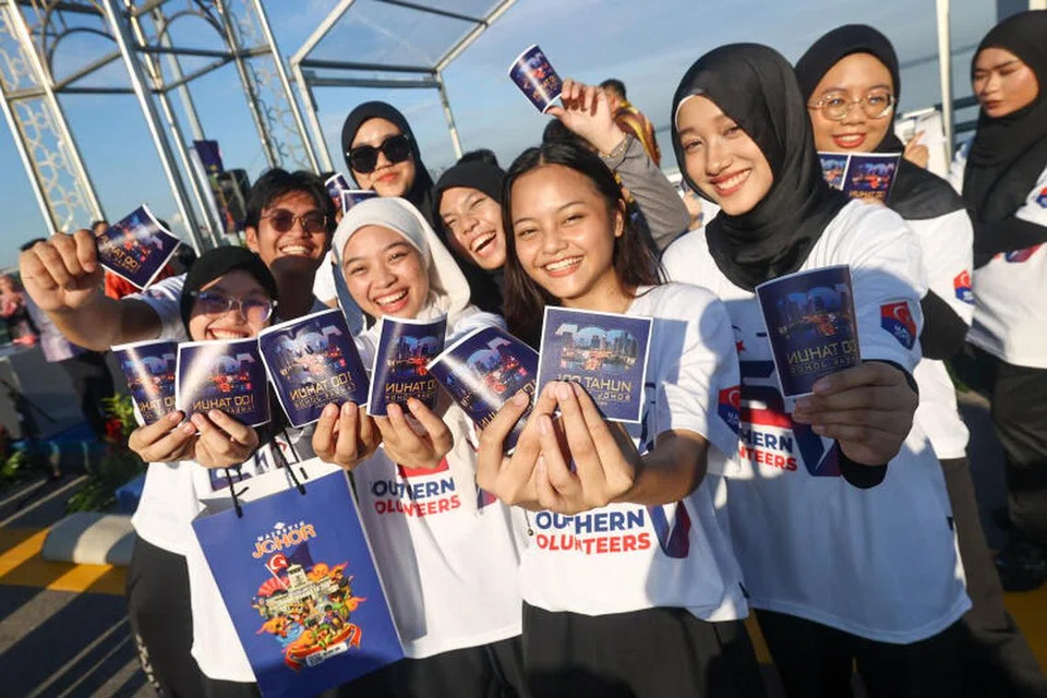 Sukarelawan dari pertubuhan sukarelawan belia Malaysia, Southern Volunteers, mengagihkan pelekat meraikan sambutan 100 tahun Tambak Johor kepada kenderaan yang keluar dari Singapura.