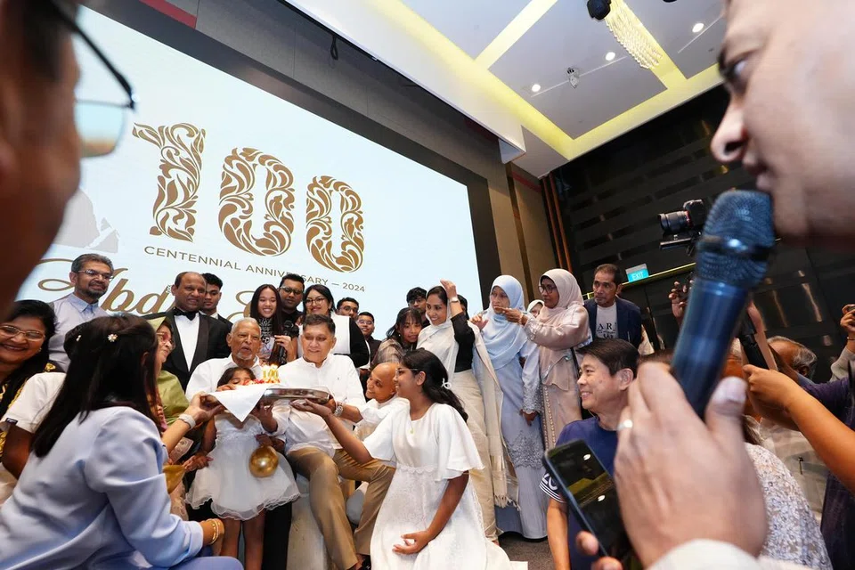 Encik Abdul Gafoore Mohamed Kassim (tengah) menerima kek istimewa sempena meraikan ulang tahun ke-100 beliau dengan disaksikan Ketua Pegawai Eksekutif (CEO) PropNex, Encik Ismail Gafoor (belakang, berjaket hitam) dan lebih 70 tetamu, merangkumi anggota keluarga, saudara-mara dan teman terdekat di Sky Ballroom, Parkroyal di Beach Road pada 16 Jun.