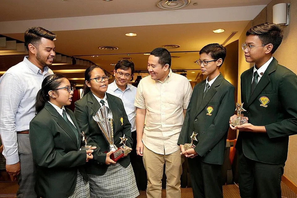 JUARA KALI PERTAMA: Pelajar Sekolah Menengah Evergreen (berjaket hijau, dari kiri) Kaisah Abdul Kadir, Nur'Ain Nadzirah Mohammed Nazir, Muhammad Imran Abrahim dan Mohammad Danial Hishamuddin, beramah tamah dengan Setiausaha Parlimen Kanan (Ehwal Dalam Negeri merangkap Kesihatan) Encik Amrin Amin (tiga dari kanan), selepas menjadi juara Bahas 4PM. - Foto 4PM