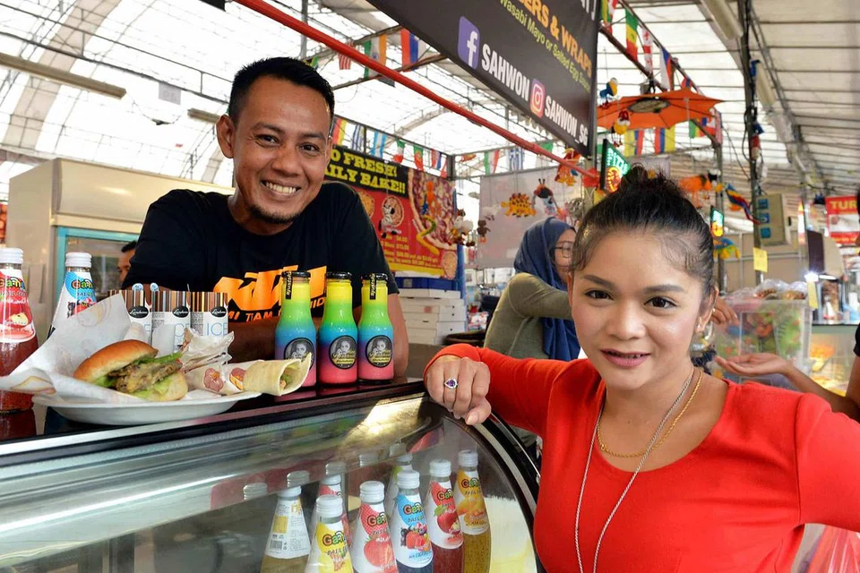 CETUS KEGILAAN BARU: Juara SG Mania, Nana Karia dan rakan niaganya, Mohamad Riduan Ishak (kiri), tidak menjangka dadih dan burger salmon yang dijual di bazar sekitar tapak lama Kampung Melayu Geylang Serai mencetus fenomena. - Foto M.O. SALLEH