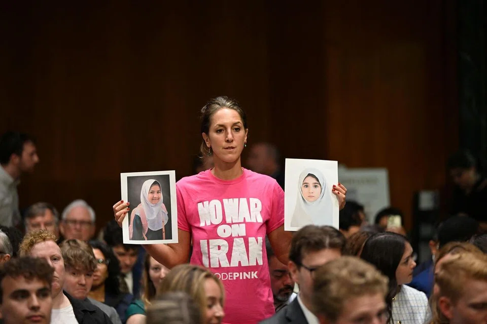 Seorang penunjuk perasaan antiperang mengangkat gambar ketika Setiausaha Pertahanan Amerika Syarikat, Pete Hegseth, memberi keterangan di hadapan Jawatankuasa Peruntukan Senat di Capitol Hill, Washington pada 21 Julai 2026. Hegseth memohon dana tambahan AS$87 bilion bagi membiayai operasi ketenteraan, termasuk perang yang semakin memuncak dengan Iran.