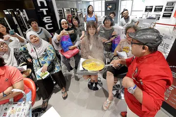 SESI MASAK PERTAMA: Cef Mel Dean (kanan) menunjukkan cara memasak Nasi Liwet Solo, Ayam Panggang Temasek dan Salsa Nanas Thailand kepada peserta yang hadir di Harvey Norman pada 25 Mac lalu. Pada sesi kedua 29 April ini, beliau menunjukkan cara memasak masakan Mexico. - Foto fail