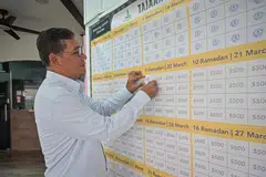 Pengerusi Masjid Alkaff Kampung Melayu, Encik Mohamed Faizul Othman, melekatkan kertas yang tertera logo masjid pada kotak kecil pada kalendar kain rentang Tajaan Ramadan, apabila jumlah sumbangan pada hari itu sudah mencukupi.