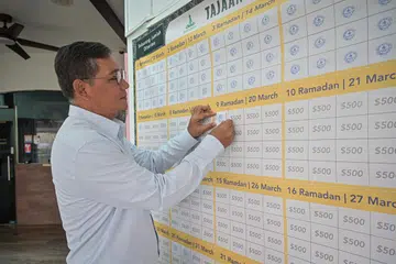 Pengerusi Masjid Alkaff Kampung Melayu, Encik Mohamed Faizul Othman, melekatkan kertas yang tertera logo masjid pada kotak kecil pada kalendar kain rentang Tajaan Ramadan, apabila jumlah sumbangan pada hari itu sudah mencukupi.