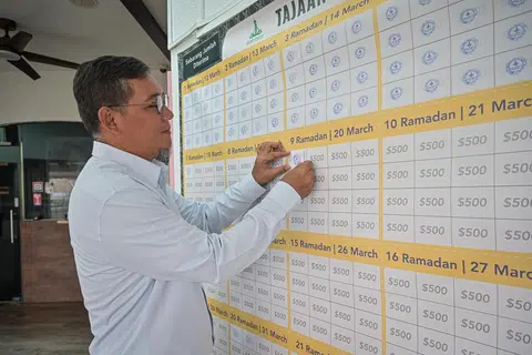 Pengerusi Masjid Alkaff Kampung Melayu, Encik Mohamed Faizul Othman, melekatkan kertas yang tertera logo masjid pada kotak kecil pada kalendar kain rentang Tajaan Ramadan, apabila jumlah sumbangan pada hari itu sudah mencukupi.