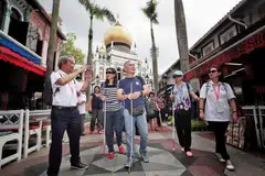JALAN KENANGAN: Encik Chhua Bak Siang (kiri), 71 tahun, memimpin golongan cacat penglihatan dari Guide Dogs Singapore melawat sekitar Bussorah Street. - Foto BH oleh KELVIN CHNG