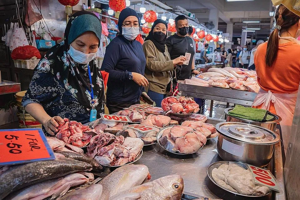 BELI BARANGAN BASAH: Pelanggan memilih ikan segar di Pasar Geylang Serai semalam. Kenaikan harga makanan menjejas bukan hanya makanan laut tetapi juga barangan kering seperti bawang merah, cili kering dan tepung gandum. - Foto BH oleh NUR DIYANA TAHA