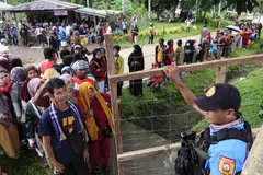 Seorang anggota polis berkawal ketika para pengundi beratur di luar pusat mengundi di bandar Panamao, wilayah Sulu, selatan Filipina pada 12 Mei 2025. Jutaan rakyat Filipina keluar mengundi pada 12 Mei dalam pilihan raya separuh penggal yang dilihat secara meluas sebagai referendum terhadap pertelingkahan hebat antara Presiden Ferdinand Marcos dengan Naib Presiden yang dipecat, Cik Sara Duterte