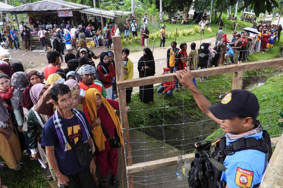 Seorang anggota polis berkawal ketika para pengundi beratur di luar pusat mengundi di bandar Panamao, wilayah Sulu, selatan Filipina pada 12 Mei 2025. Jutaan rakyat Filipina keluar mengundi pada 12 Mei dalam pilihan raya separuh penggal yang dilihat secara meluas sebagai referendum terhadap pertelingkahan hebat antara Presiden Ferdinand Marcos dengan Naib Presiden yang dipecat, Cik Sara Duterte