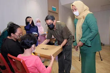 BAWA KECERIAAN: Dr Faishal (dua dari kanan) dan Cik Haslinda (kanan) memberikan komputer riba tajaan Far East Organisation kepada sekumpulan anak-anak pesalah dadah semasa acara Projek Pelita Hati di Kelab Masyarakat Nee Soon Central semalam. 