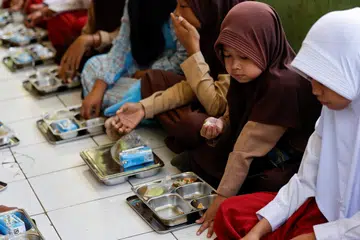Shakila Fitriyani, 11 tahun, bersama pelajar lain, menjamah makanan dari percubaan program makanan berkhasiat percuma semasa waktu rehat di sekolah di Sukabumi, wilayah Jawa Barat, Indonesia, pada 26 September 2024.
