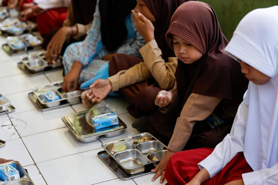 Shakila Fitriyani, 11 tahun, bersama pelajar lain, menjamah makanan dari percubaan program makanan berkhasiat percuma semasa waktu rehat di sekolah di Sukabumi, wilayah Jawa Barat, Indonesia, pada 26 September 2024.