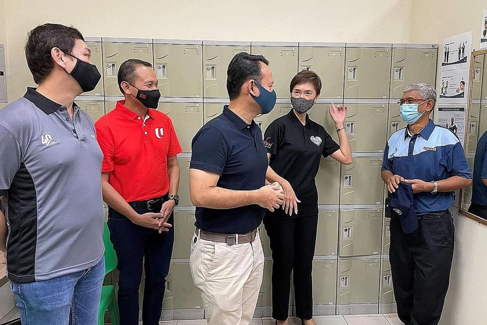 PERTINGKAT SEKITARAN KERJA: Encik Fahmi Aliman (berbaju merah) bersama Encik Zaqy Mohamad (tengah) dan Cik Josephine Teo, mantan Menteri Tenaga Manusia yang kini Menteri Perhubungan dan Penerangan merangkap Menteri Kedua Ehwal Dalam Negeri, mengunjungi tempat rehat untuk pekerja pembersihan di Jurong Point pada 14 Mei. - Foto FAHMI ALIMAN / FACEBOOK