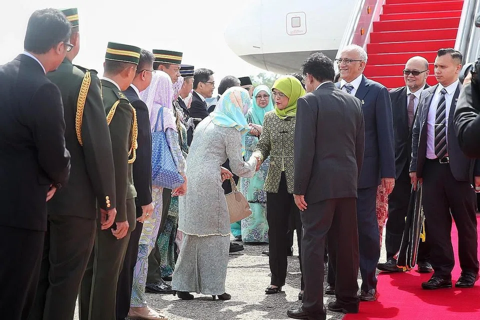 PERKUKUH HUBUNGAN: Puan Halimah (tengah) bersama suami Encik Mohamed Abdullah Alhabshee (tiga dari kanan) disambut pegawai dan tokoh kanan Brunei di Lapangan Terbang Antarabangsa Brunei semalam. - Foto BH oleh GAVIN FOO