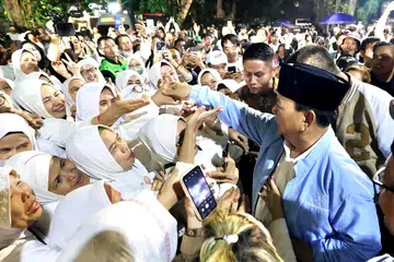 HULUR BANTUAN: Dalam usaha memerangi masalah kekurangan zat makanan, calon presiden, Encik Prabowo Subianto (bersongkok, berbaju biru), menjanjikan program makan siang percuma untuk pelajar sekolah dan pesantren jika beliau memenangi pilihan raya.