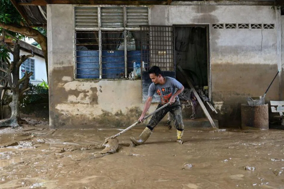 Penduduk Mohd Hazwan Yahaya, 34 tahun, membersihkan kediamannya di Kuala Terengganu, Terengganu, yang diselaputi lumpur akibat banjir. 
