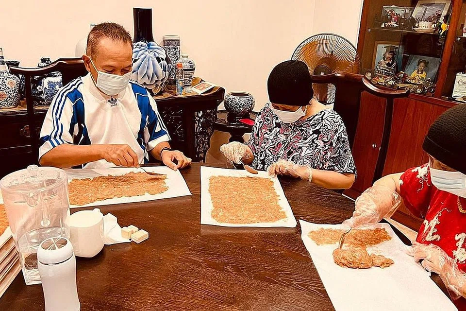 PROSES BUAT 'BAK KWA': Encik Ismail (kiri), isterinya, Cik Noraini Mohamed Noor (tengah) dan adik Cik Noraini sedang meleperkan daging 'bak kwa' sebelum daging itu dibakar.