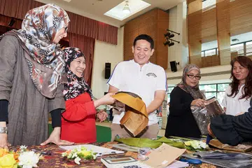 SEMUA DITAJA: Pengasas bersama Teag Pte Ltd Cik Haslina Abdul Hamid (kiri) menunjukkan fabrik yang ditawarkan kepada Encik Amrin di Bazaar Tempahan Baju Raya di Kelab Masyarakat Woodlands semalam. - Foto BH oleh LIN ZHAOI WEI