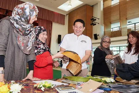 SEMUA DITAJA: Pengasas bersama Teag Pte Ltd Cik Haslina Abdul Hamid (kiri) menunjukkan fabrik yang ditawarkan kepada Encik Amrin di Bazaar Tempahan Baju Raya di Kelab Masyarakat Woodlands semalam. - Foto BH oleh LIN ZHAOI WEI