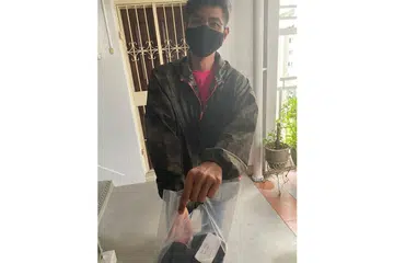 HULUR BANTUAN: Encik Nazri menghulurkan kek dan biskut yang dibuatnya sendiri kepada keluarga kurang bernasib baik. - Foto ihsan NAZRI ARSHAD 