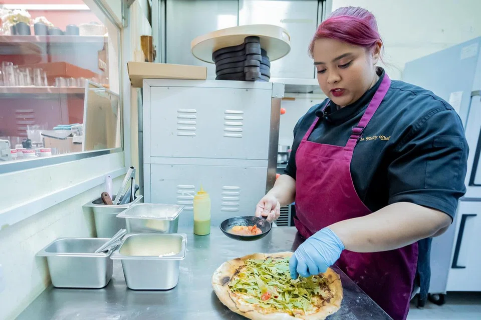 Pemilik The Fluffy Chef, Cik Zarifah Abdul Rasid, sedang menyiapkan hidangan Piza Pesto Burrata. 